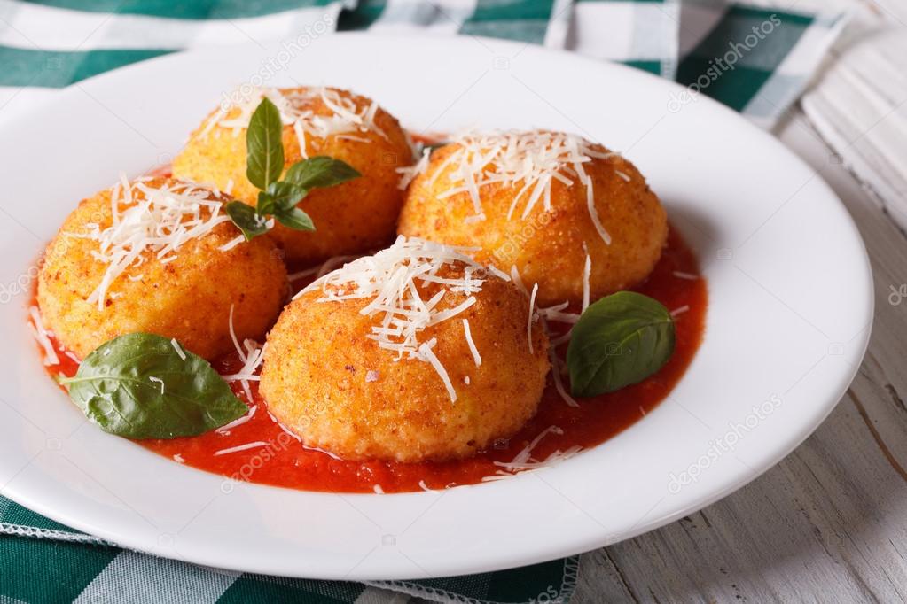 Delicious fried arancini rice balls in tomato sauce close-up. ho