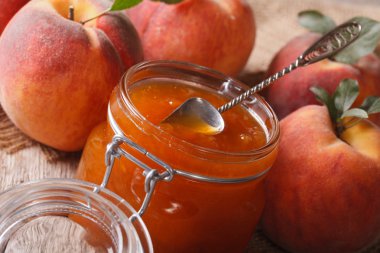 Peach jam in a glass jar close up on the table. Horizontal