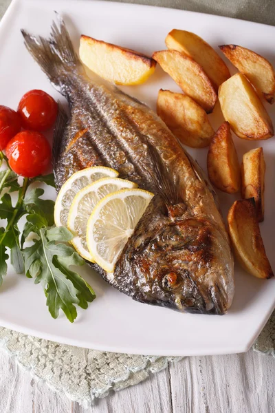 Жареная рыба Дорадо с жареной картошкой и лимонным крупным планом. verti — стоковое фото