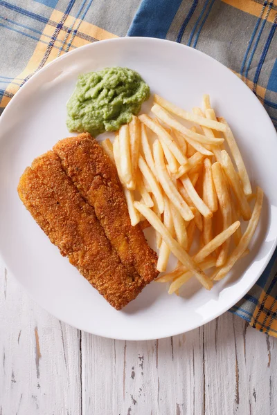 English food: fried fish in batter with chips close-up. vertical