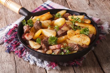country fried potatoes with meat and bacon in a pan closeup. hor