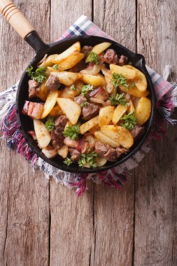 rustic fried potatoes with meat in a pan. vertical top view