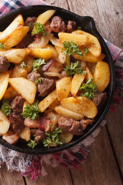 fried potatoes with meat and bacon in a pan close-up. vertical t