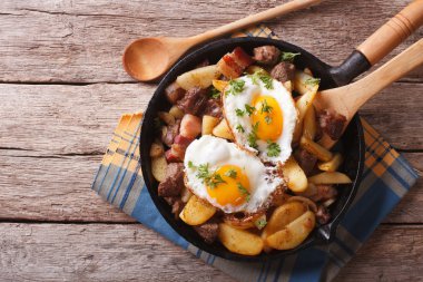  fried potatoes with meat, bacon and eggs in a pan. horizontal t
