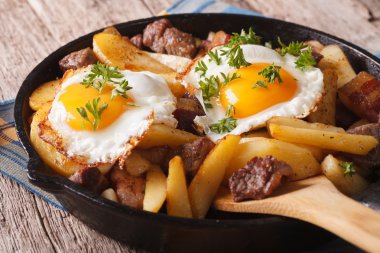 Austrian food: fried potatoes with meat and eggs in a pan closeu