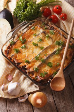 Greek moussaka closeup in baking dish and ingredients. vertical