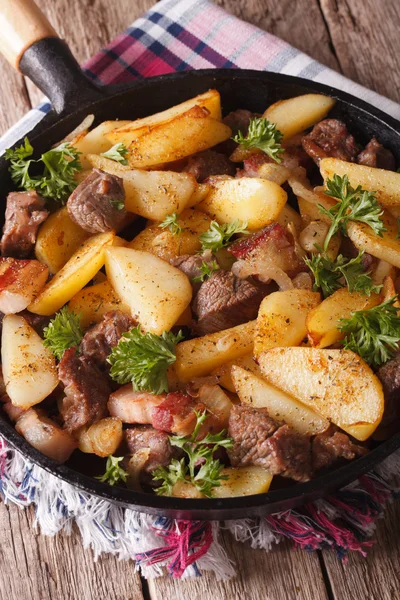 Fried potatoes with meat and bacon served in a pan close-up. ver — Stock Photo, Image