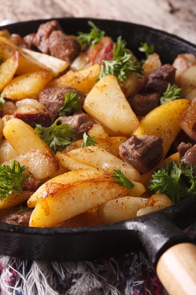 Fried potatoes with meat and bacon in a pan close-up. Vertical — Stock Photo, Image