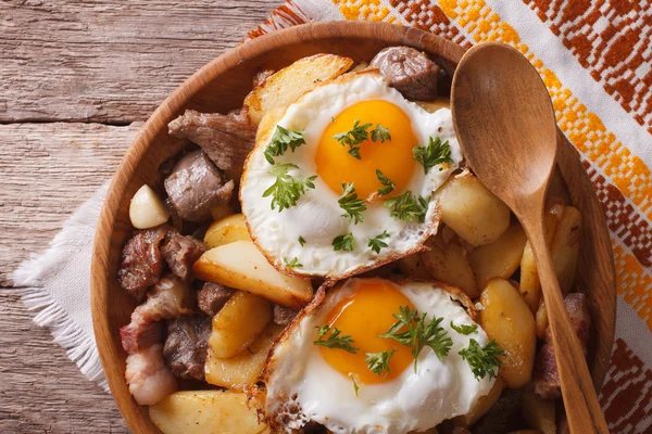 Fried potatoes with meat and eggs close-up in a bowl. horizontal — 图库照片