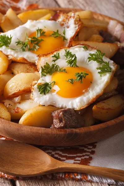 Fried potatoes with meat, bacon and eggs closeup in a wooden bow — Stock Photo, Image