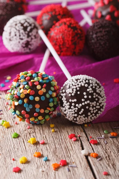 Chocolate cake pops with candy sprinkles macro on an table. vert — Zdjęcie stockowe