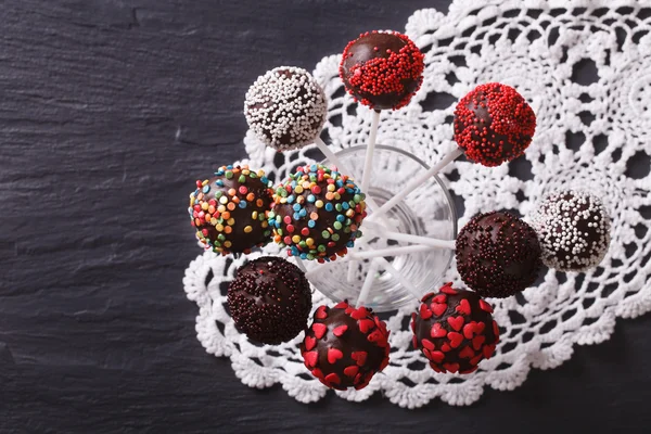 Chocolate cake pops with candy sprinkles on a lace doily. horizo — Stock Photo, Image