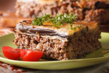 Piece of moussaka with tomatoes on a plate macro. horizontal