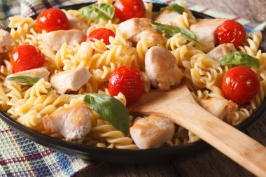 Italian pasta fusilli with chicken and tomatoes macro on a plate