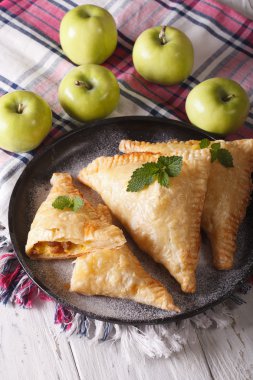 Delicious pie turnover with apples and raisins close-up. Vertica