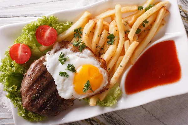 Beefsteak, fried egg and potatoes on a plate closeup. horizontal — Stock Photo, Image