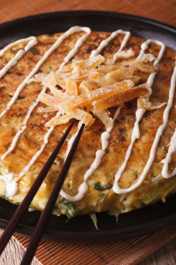 Japon pizza: okonomiyaki bir tabak ve yemek çubukları. Dikey