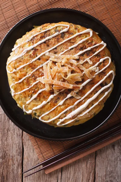 Japanese okonomiyaki on a table close-up. vertical top view — Stock Photo, Image