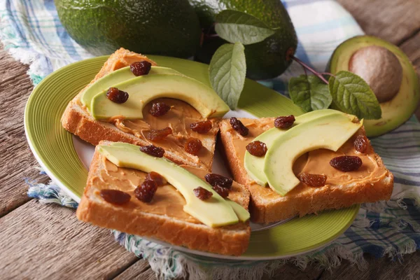 Здоровый сэндвич с арахисовым маслом, авокадо и изюмом. horiz — стоковое фото