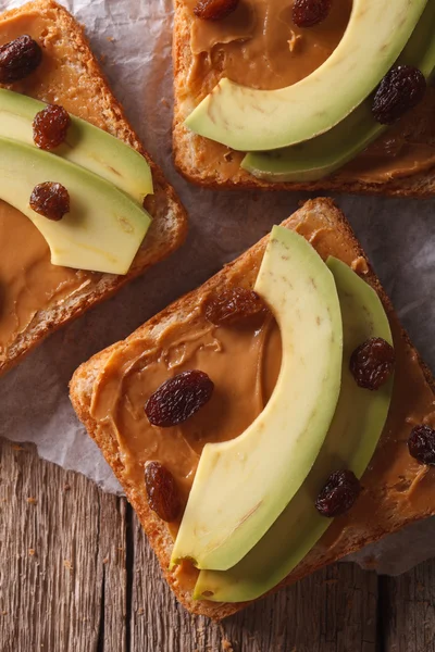 Sándwich con aguacate, crema de cacahuete y pasas macro. vertical t — Foto de Stock