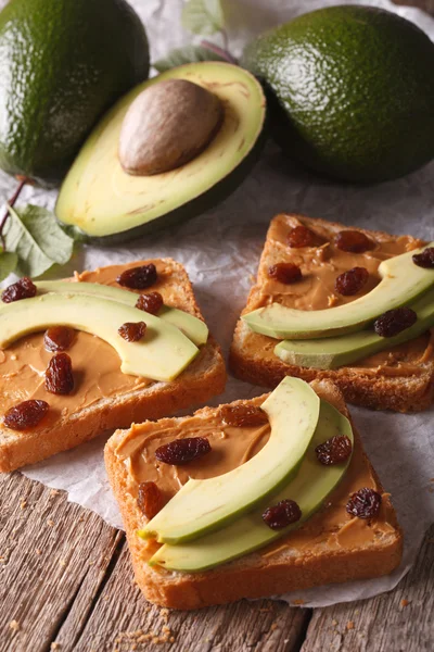 Sandwiches con aguacate, crema de maní y pasas de uva de cerca. verti — Foto de Stock