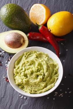 Traditional guacamole sauce with ingredients close-up. vertical