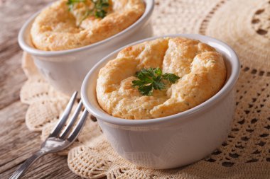 Two baked cheese souffle in a white pot close-up. horizontal clipart