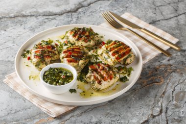 Masadaki tabakta sarımsak, ot ve sebze yağından yapılmış ızgara tavuk butları. Yatay