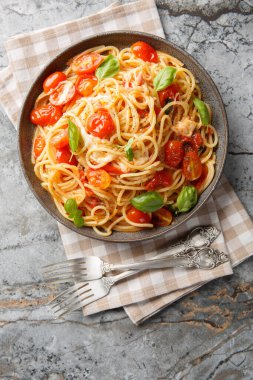 Pasta Margherita with fresh tomatoes, mozzarella cheese, basil and olive oil close-up in a plate on the table. Vertical top view from abov