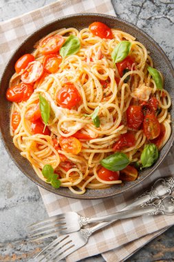 Margherita Spaghetti made with tomatoes, basil, and mozzarella closeup on the plate on the table. Vertical top view from abov