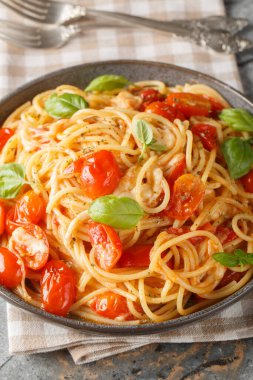 Margherita Spaghetti made with tomatoes, basil, and mozzarella closeup on the plate on the table. Vertica
