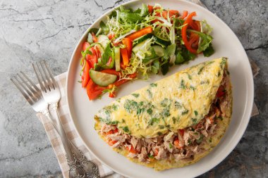 Konserve ton balığı ve biberle doldurulmuş omlet ve masada yakın plan sebze salatasıyla servis edilmiş. Yukarıdan yatay üst görünüm