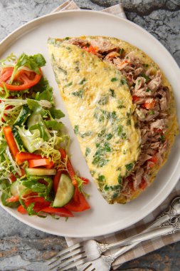 Taze sebze salatasıyla servis edilen konserve ton balıklı omlet masanın üzerindeki tabakta. Yukarıdan dikey üst görünüm