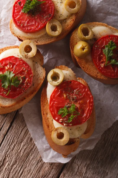 Bruschetta con tomates, aceitunas y mozzarella primer plano. vertical —  Fotos de Stock