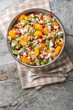 Ispanaklı kinoa salatası, feta, mandalina, nar ve şam fıstığı, masanın üstünde yakın plan. Yukarıdan dikey üst görünüm