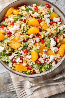 Kış Nar Portakallı kinoa salatası, ıspanak, feta ve fıstıklı masaya yakın çekim. Yukarıdan dikey üst görünüm