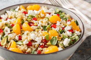 Ispanaklı diyet kinoa salatası, feta, mandalina, nar ve limonlu yoğurt soslu şam fıstığı, masada yakın plan. Yatay