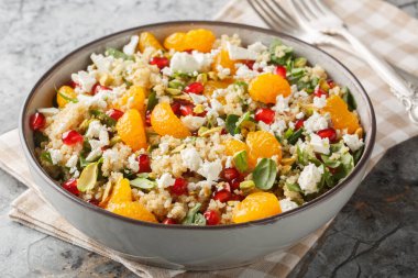 Nar ve portakallı kinoa salatası. Masanın üzerinde ıspanak, feta ve çıtır şam fıstığı var. Yatay