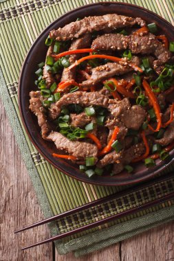 Bulgogi beef slices fried with sesame close-up on a plate. verti