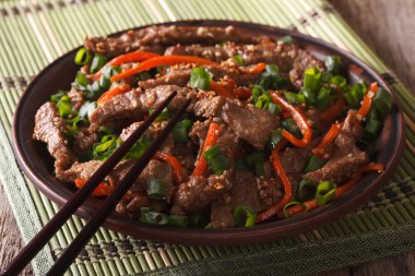 Asian cuisine: slices of beef fried with sesame and carrot close