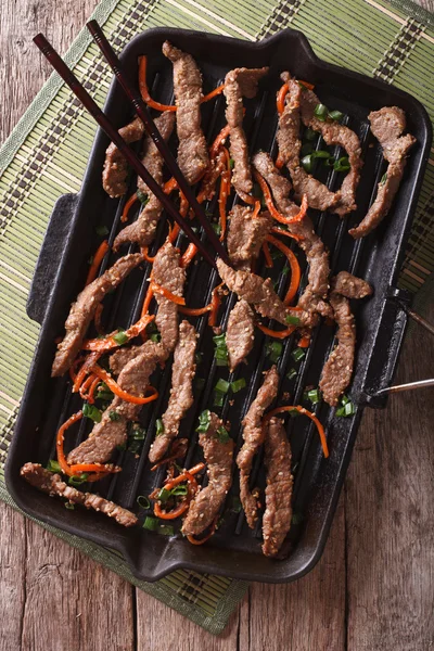 Korean Food: Bulgogi beef with carrot on grill pan closeup. Vert — Stock Photo, Image