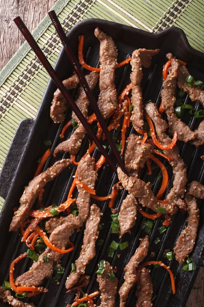 Korean Food: Bulgogi beef with carrot on grill pan macro. Vertic — Stock Photo, Image