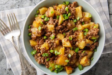 Basit ve sağlıklı yiyecekler: Kızarmış patates kıymalı ve yeşil soğanlı, yakın plan, masanın üstünde. Yukarıdan yatay üst görünüm