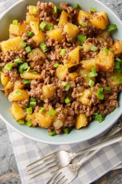 Bir tavada sığır eti ve patates, masanın üzerindeki tabağa yakın bir tava yemeğidir. Yukarıdan dikey üst görünüm