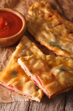 İtalyan pizza calzone salam ve peynir yakın çekim ile kesti. Dikey