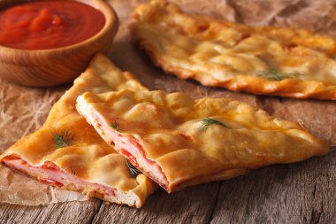 İtalyan pizza calzone salam ve peynir yakın çekim ile kesti. Horizont