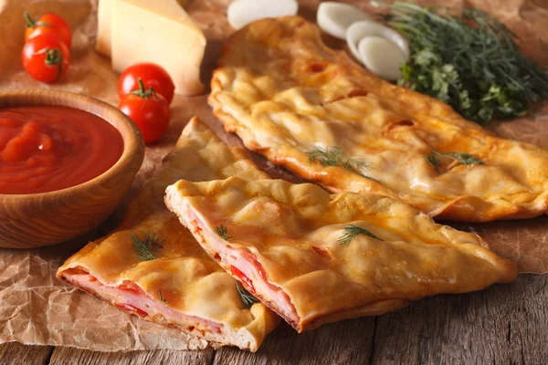 Вырезать итальянскую пиццу calzone с ветчиной крупным планом и ингредиентами. hori — стоковое фото