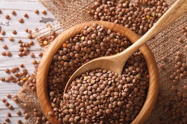 Raw brown lentils in a wooden bowl close-up. horizontal top view — Stock Photo, Image
