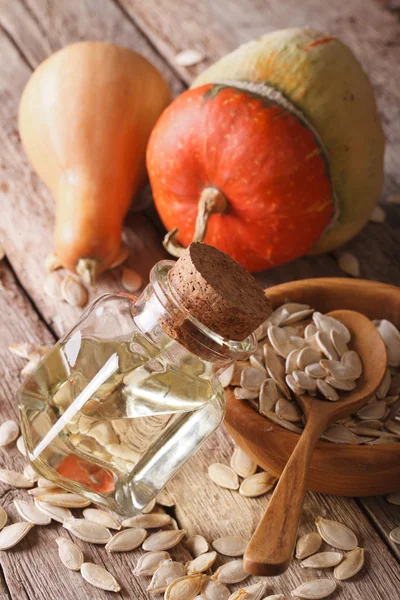 Pumpkin seed oil in a glass jar on the table close-up. vertical — Stock Photo, Image