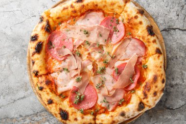 Masanın üzerinde jambonlu, jambonlu, jambonlu ve jambonlu yanmış et pizzası. Yukarıdan yatay üst görünüm
